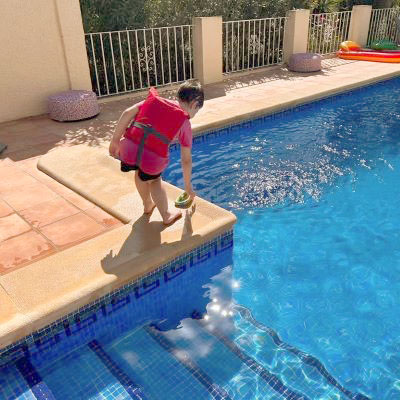 Kind am Pool mit Schwimmweste